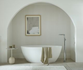 A towel on the side of bath in a curved alcove