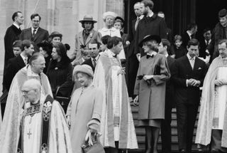 A black and white photo of numerous members of the Royal Family standing on the stairs of St. George's Chapel on Christmas Day, including the Queen Mother, Prince Charles, Princess Diana and Princess Anne