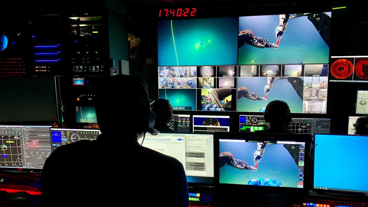 researchers work in a room full of computer screens monitoring the exploration of the wreck
