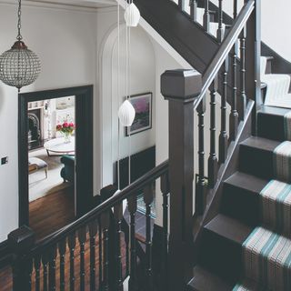 A black-painted staircase with a striped runner leading to a hallway