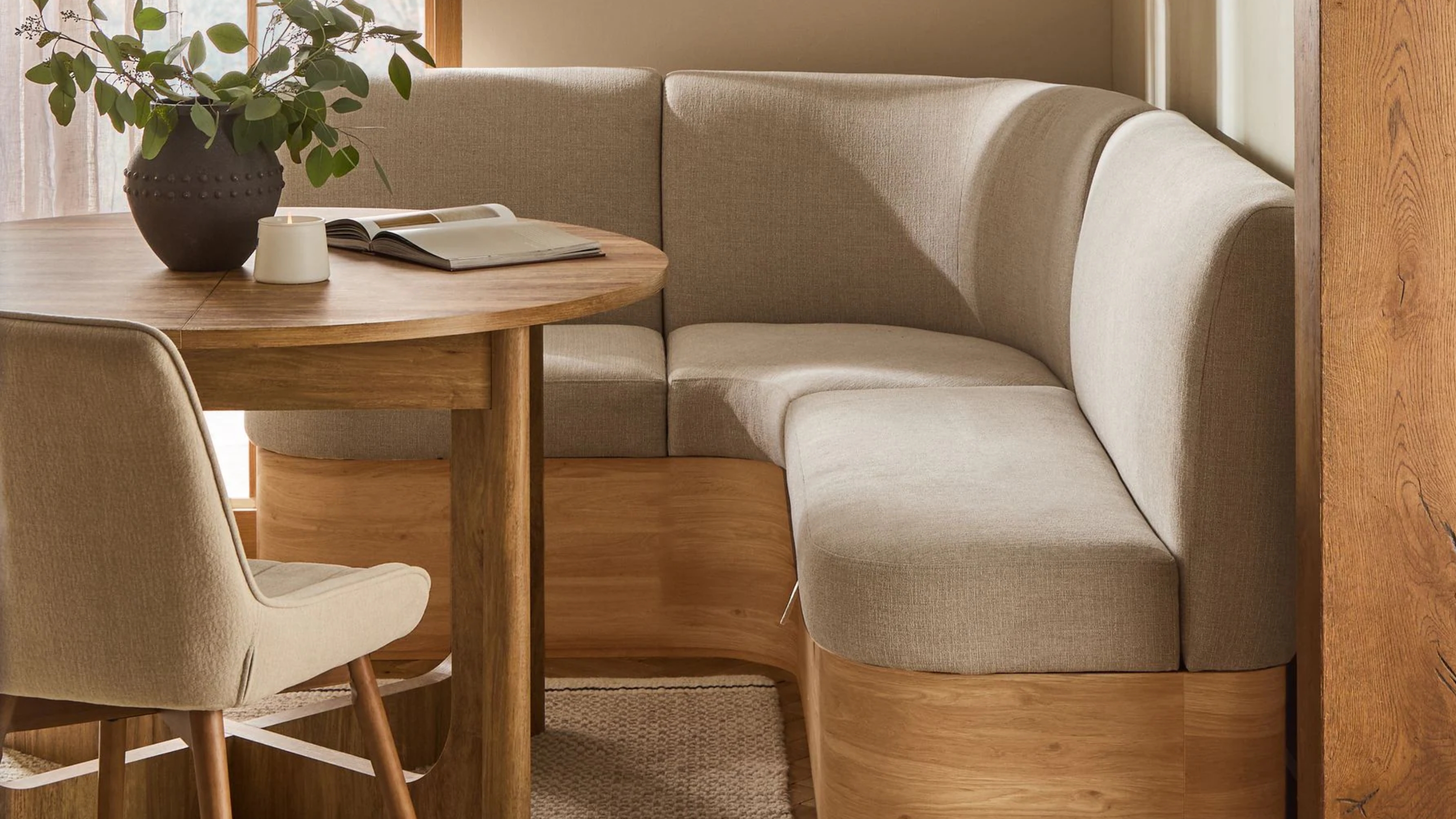 a dining table with a neutral banquette with wood base