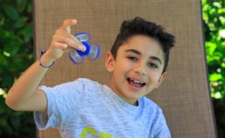 Young boy playing with a fidget spinner.