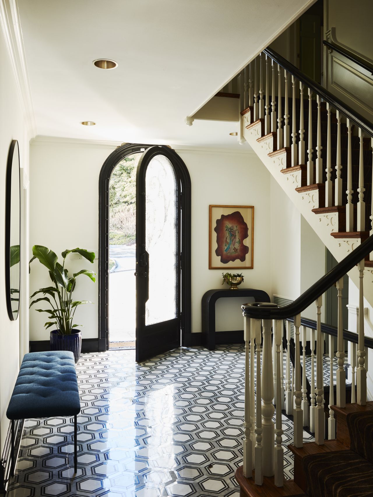 An entrance with blue-patterned tiles, black framed main door and cream walls