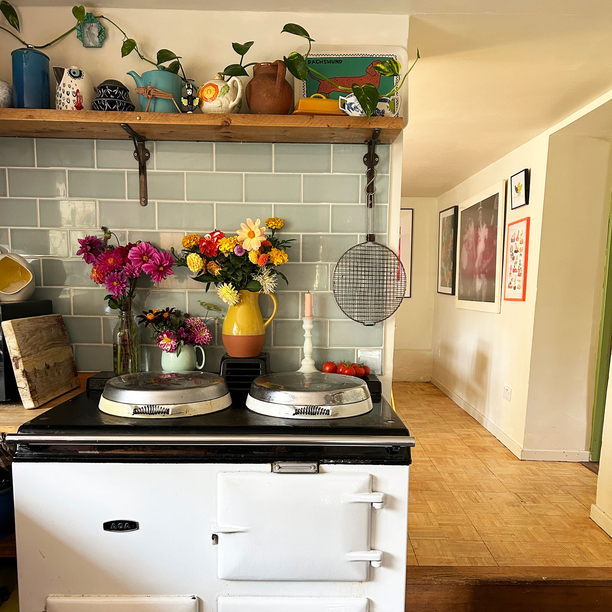 Vases on flowers in front of pale green tiled splashback on top of white AGA