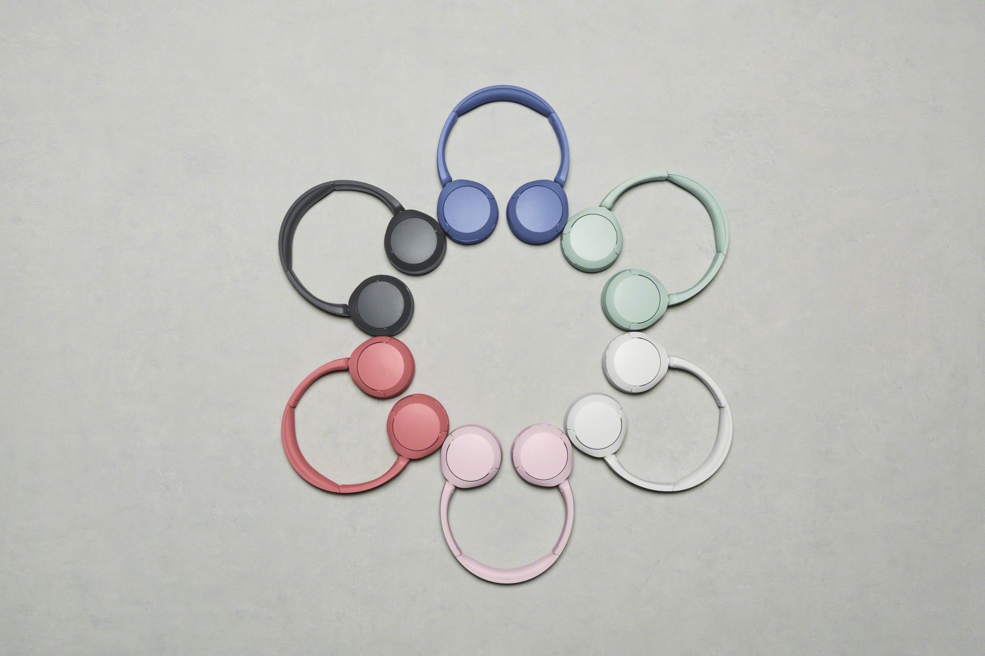 Sony WH-CH530N headphones in different colors, arranged in a circle to form a flower shape, on a gray floor