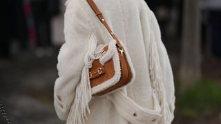 street style of person wearing fringed coat and brown fur bag