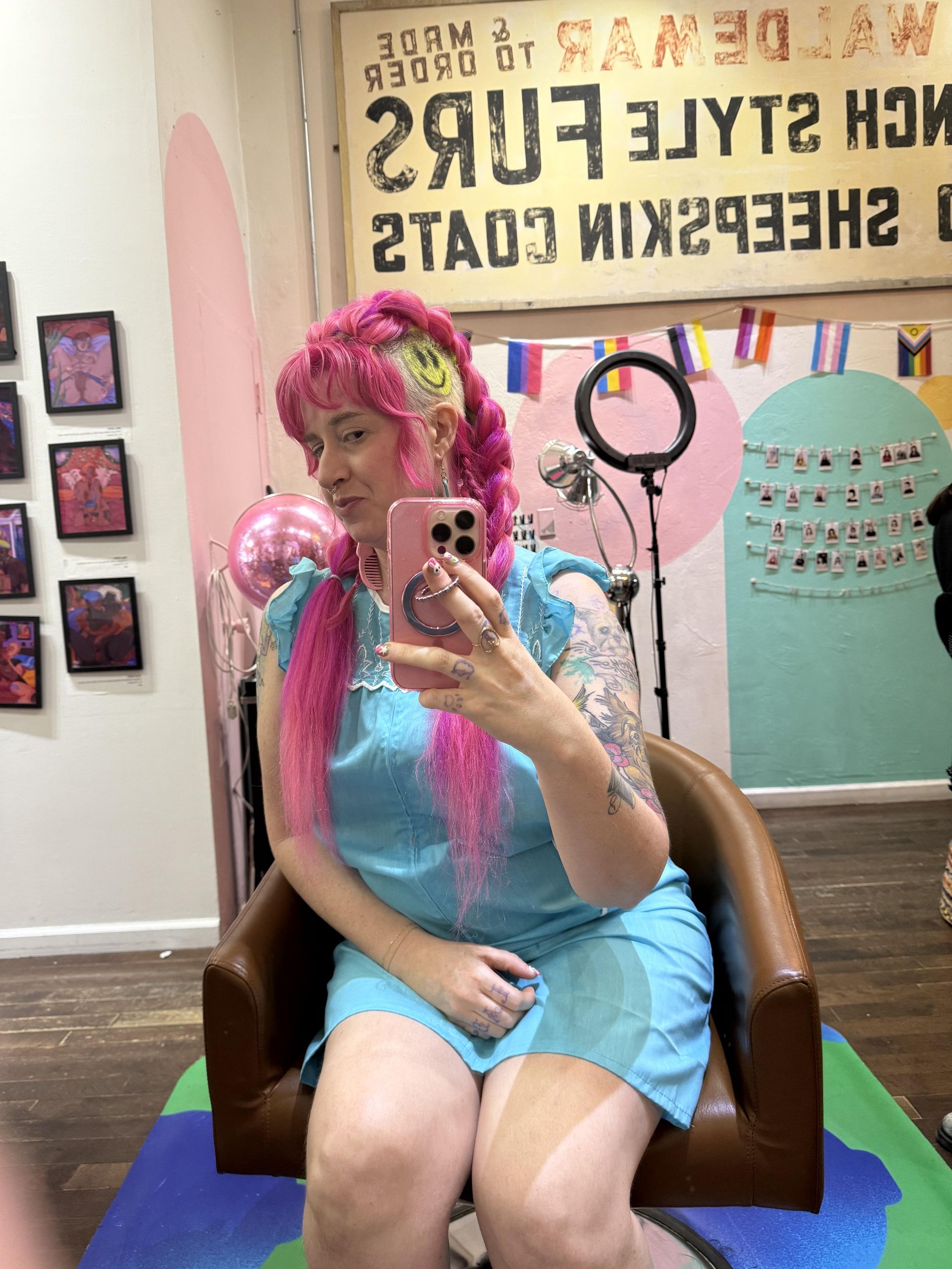 Mags Naylor sitting in salon chair with two bright pink braids.