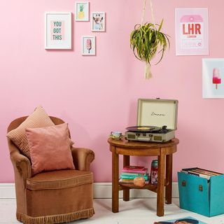 room with wooden table sofa cushions and pink wall