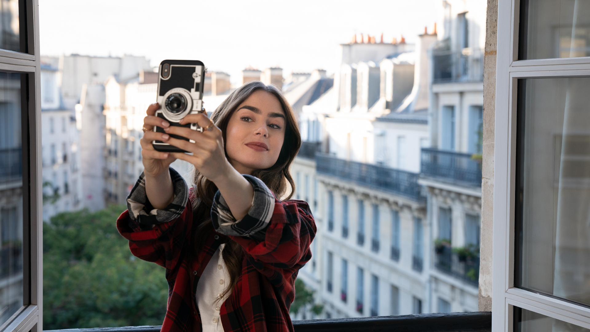 Emily in Paris holding an iPhone taking a selfie