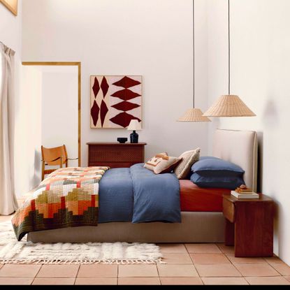 White room with grey bed, blue bedding and patchwork quilt