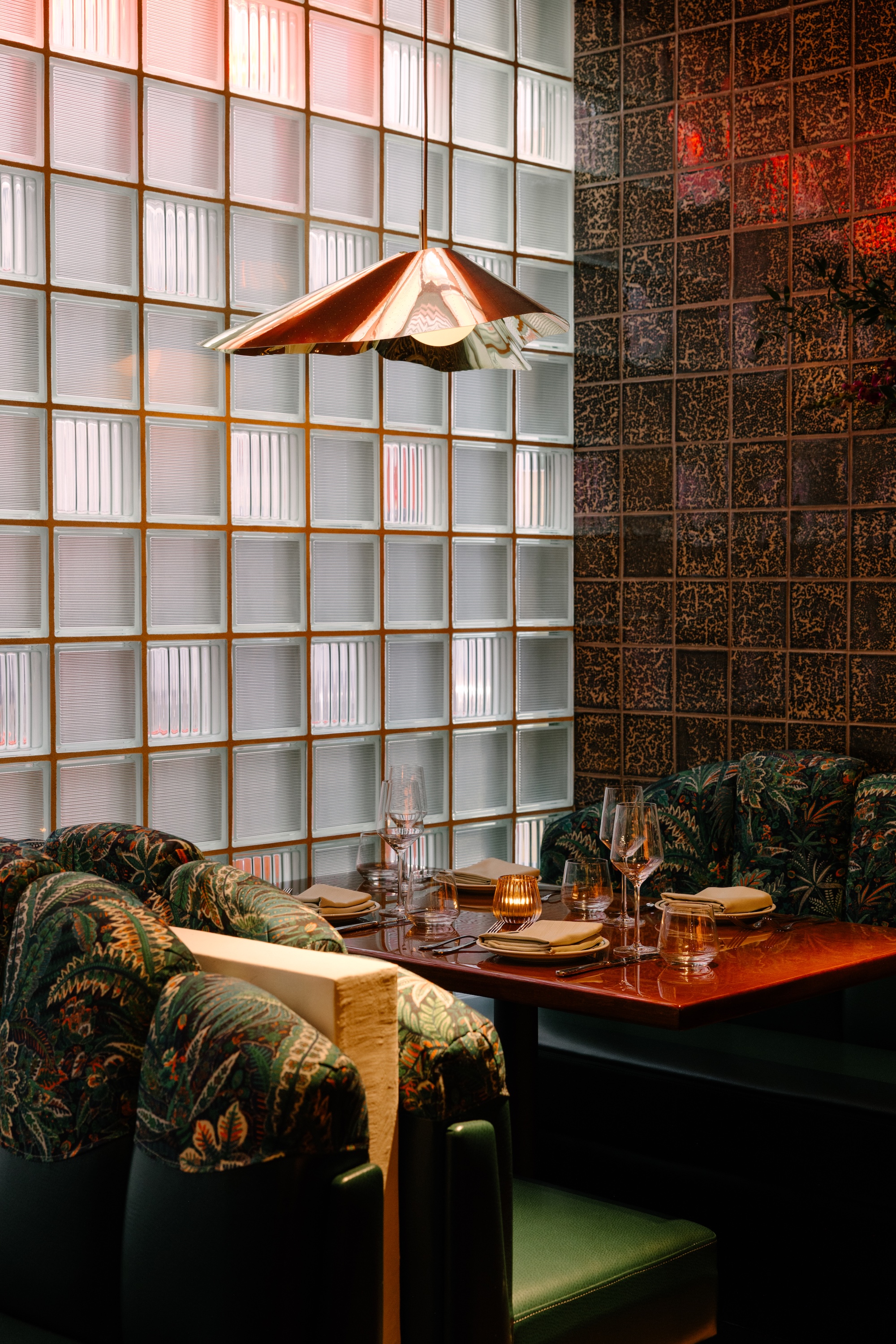 Bad Roman Los Angeles interior with floral booths, a glass brick wall and a fan shaped light fixture