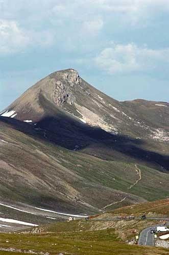 The riders miniaturized by the enormity of the Swiss Alps.
