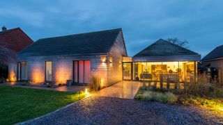 garage conversion on barn with large glass frontage and pitched wooden clad roof