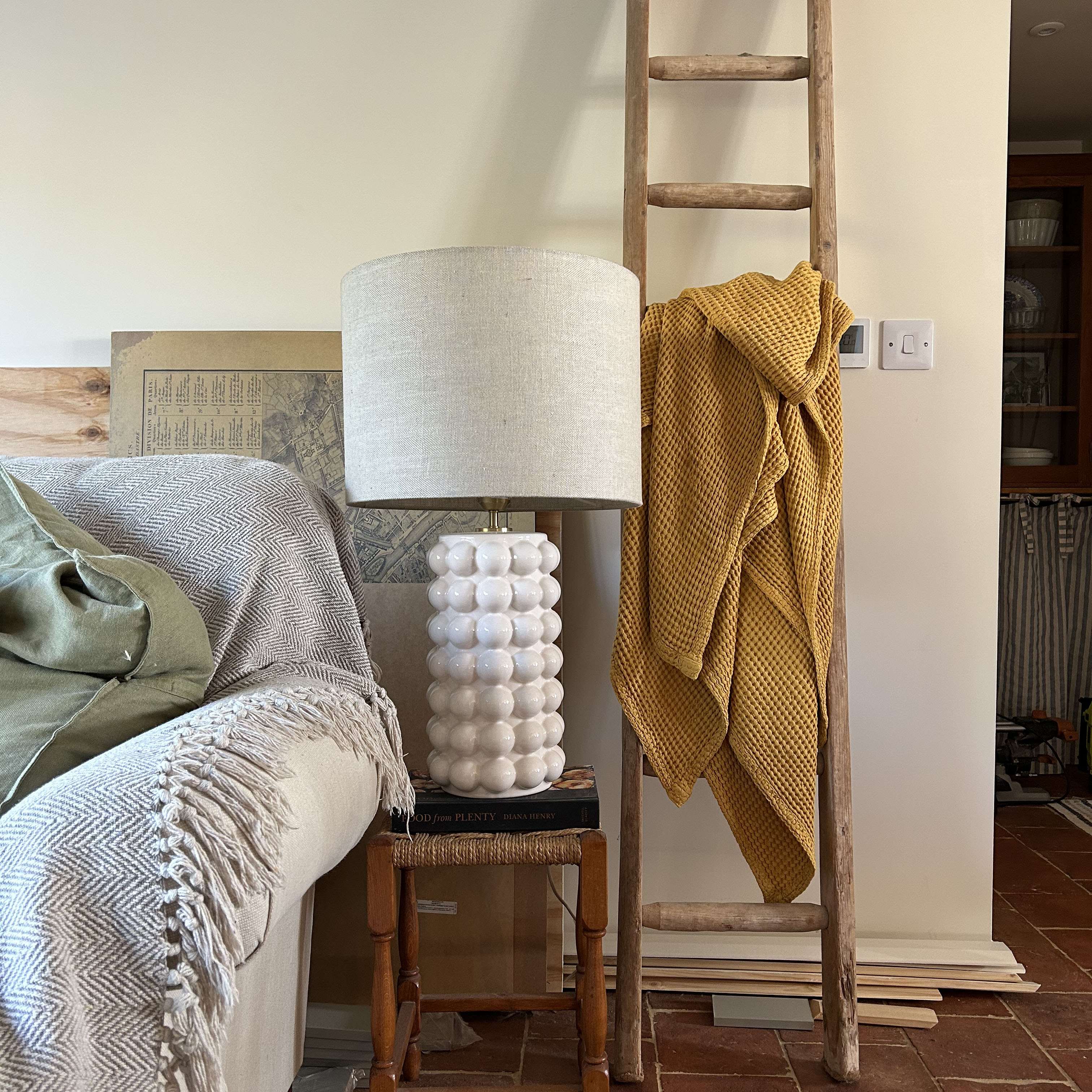 white lamp on a stool at the end of a sofa