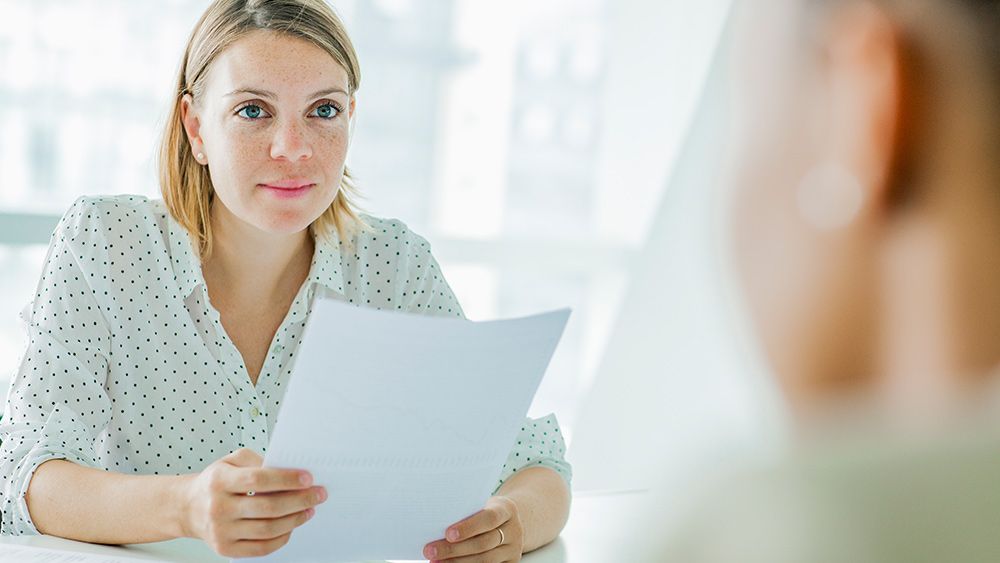 A woman reviews a job candidate&#039;s creative résumé