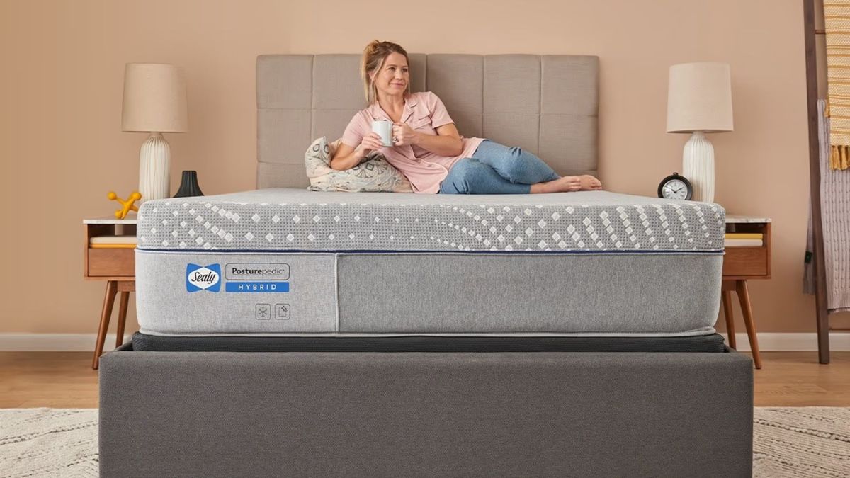 Woman sits on the Sealy Posturepedic Hybrid Mattress