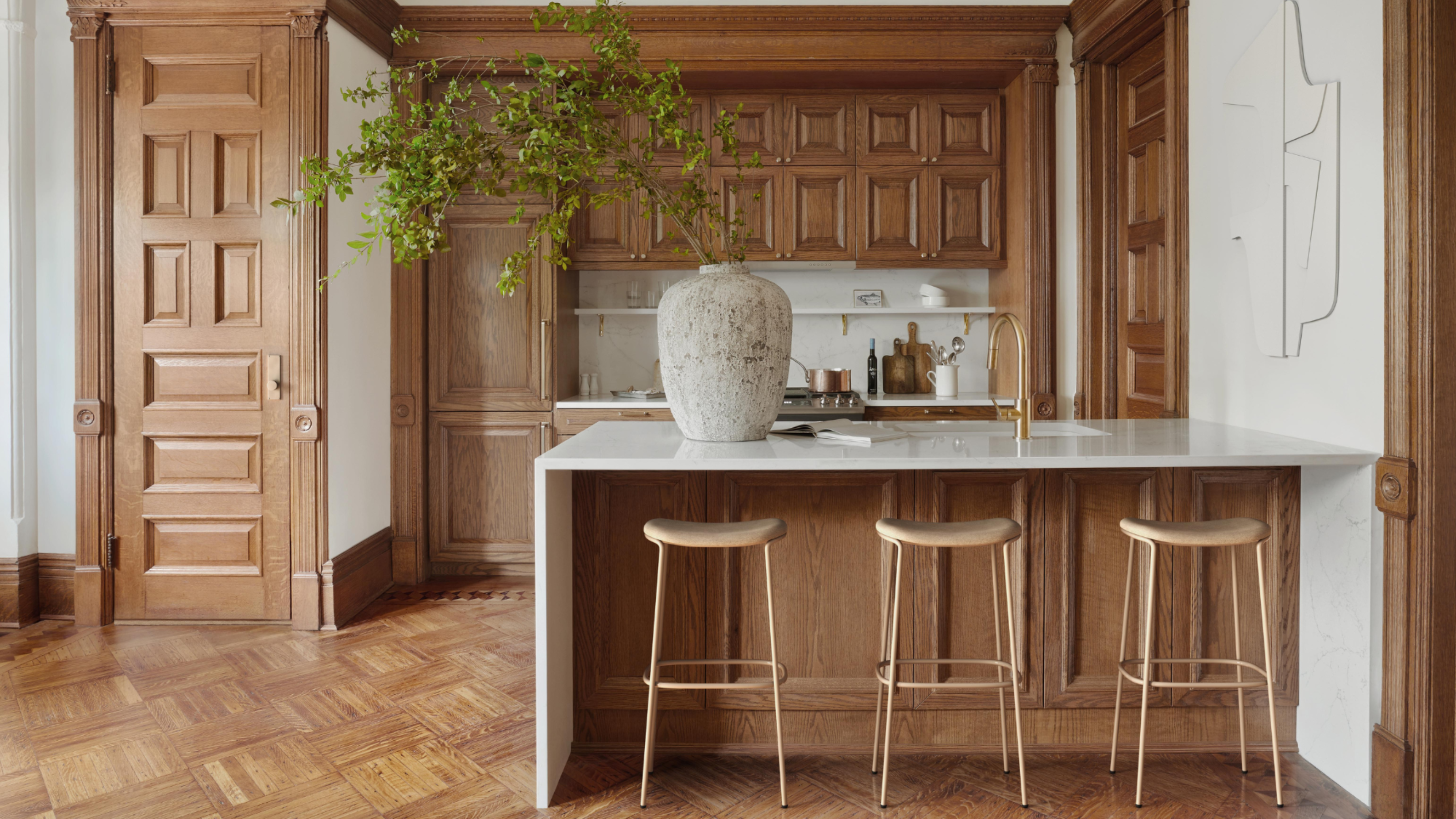 An all wood panelled kitchen with matching doors and floor, white walls, and a marble countertop