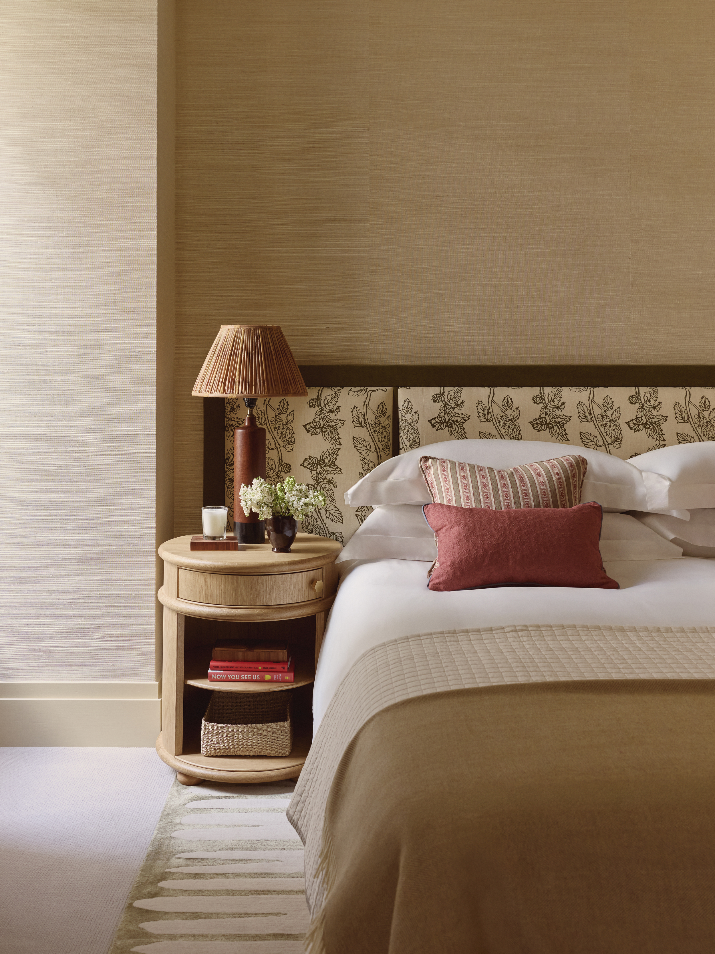 A bedroom with a vintage lamp next to a bed with a padded headboard