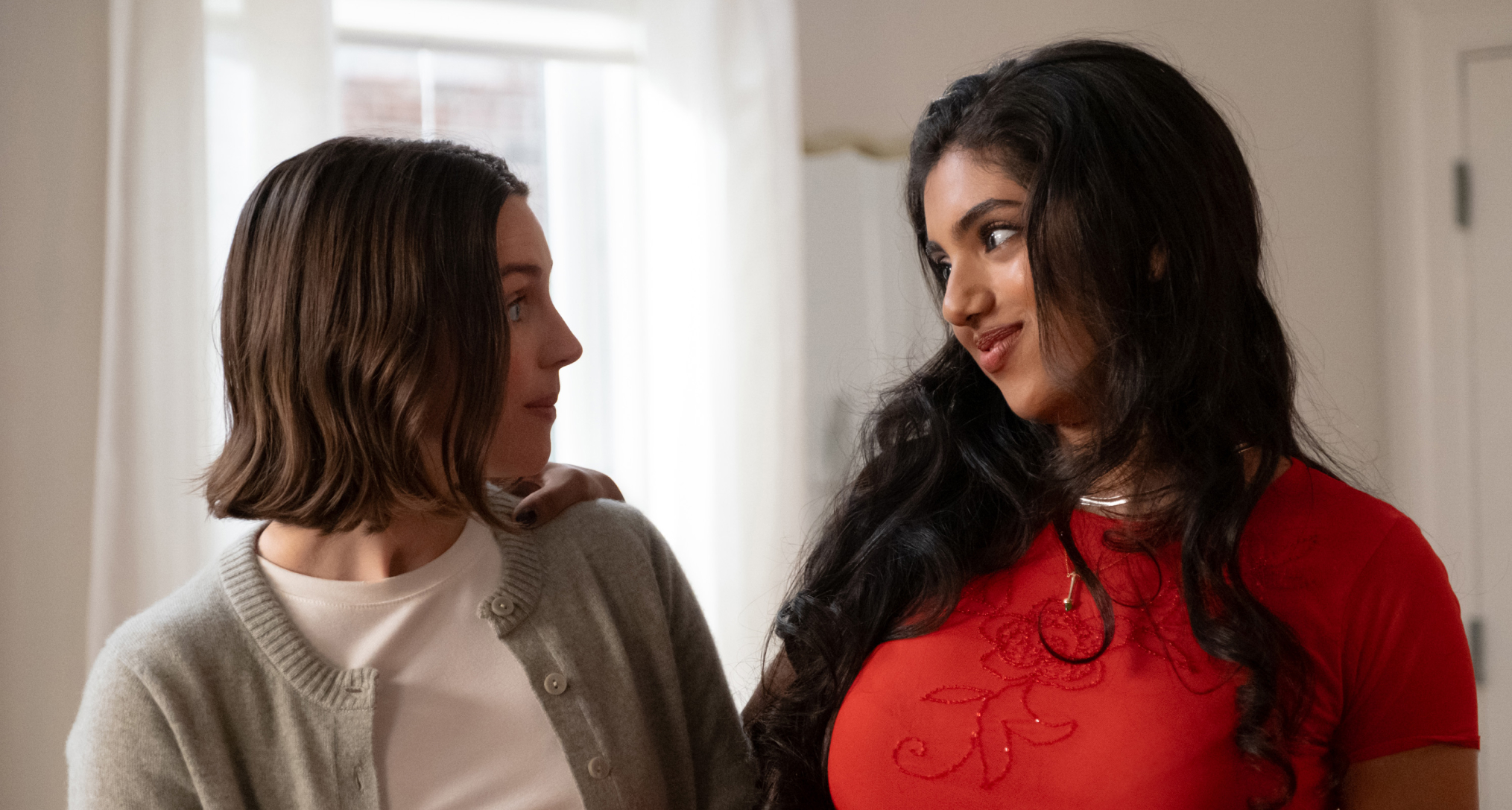 ella hunt as aj and avantika as abby looking at each other and smirking in their apartment in not suitable for work