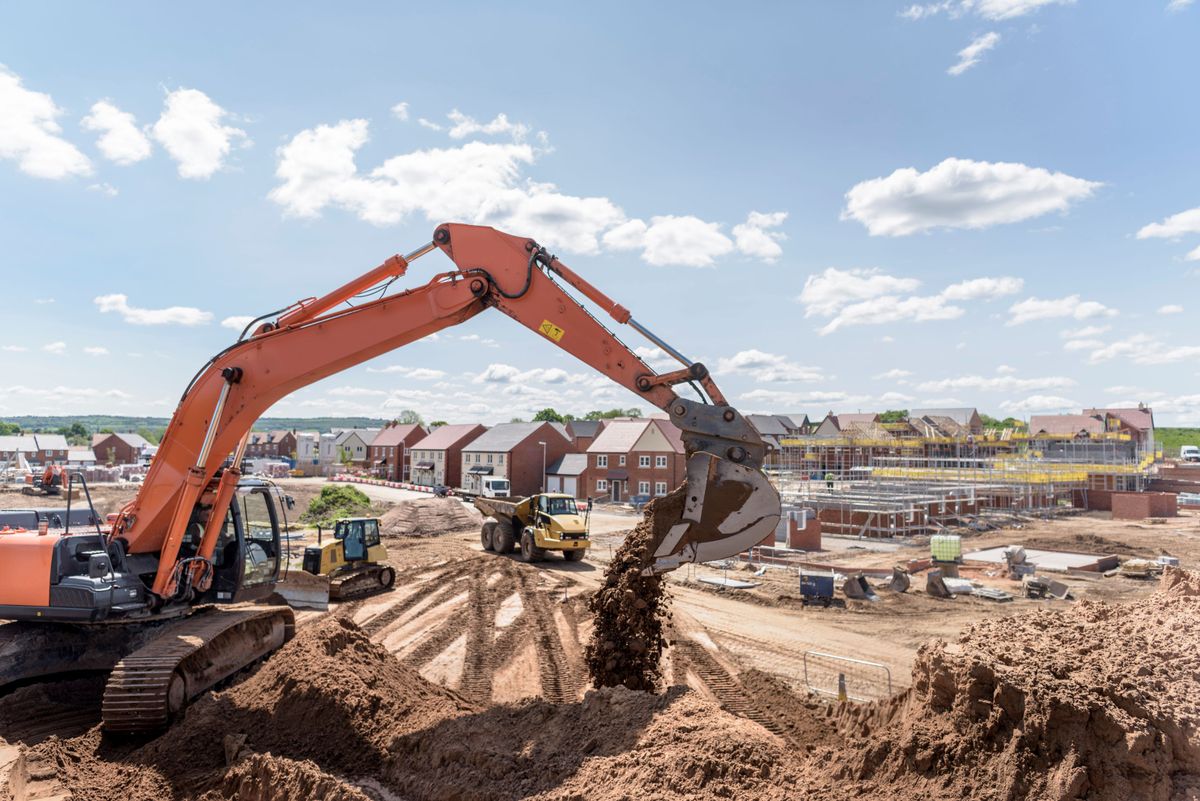 Levelling up an area by using an excavator to move earth on housing building site