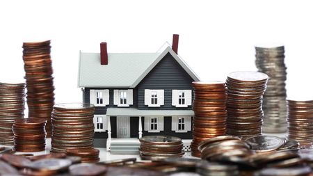 Photo illustration of a house surrounded by stacks of coins