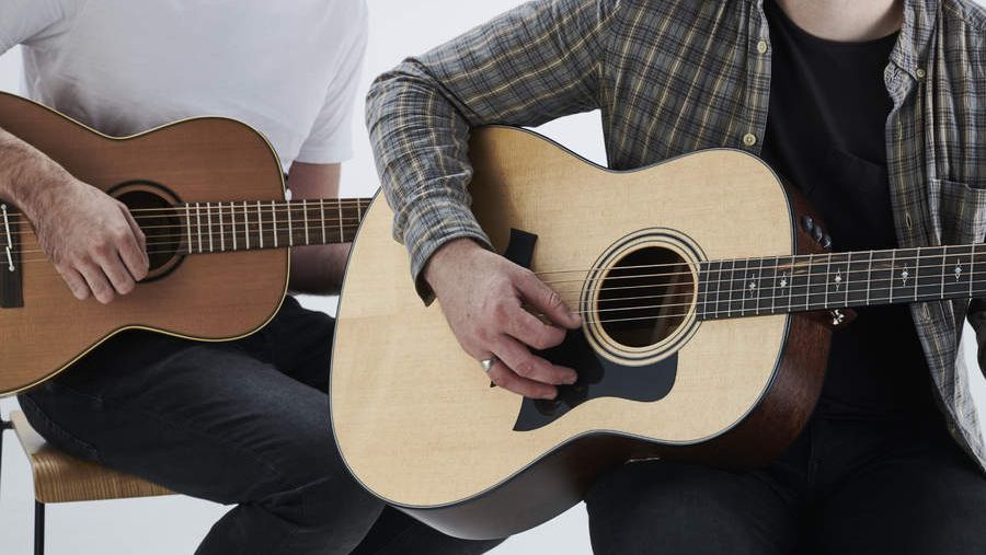 Two staff writers playing acoustic guitar together 