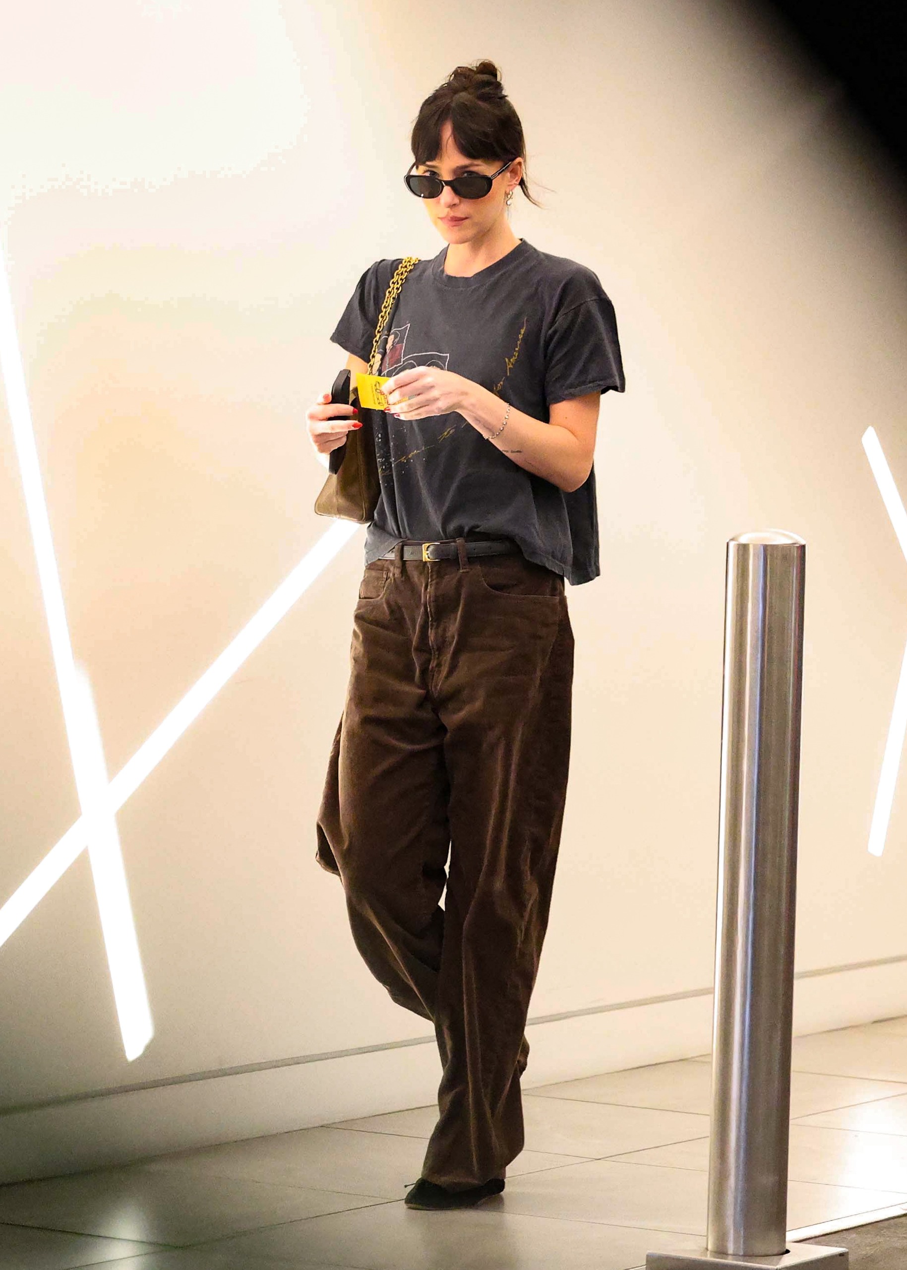 Dakota Johnson wore an oversized graphic tee with brown corduroy jeans and a Valentino bag