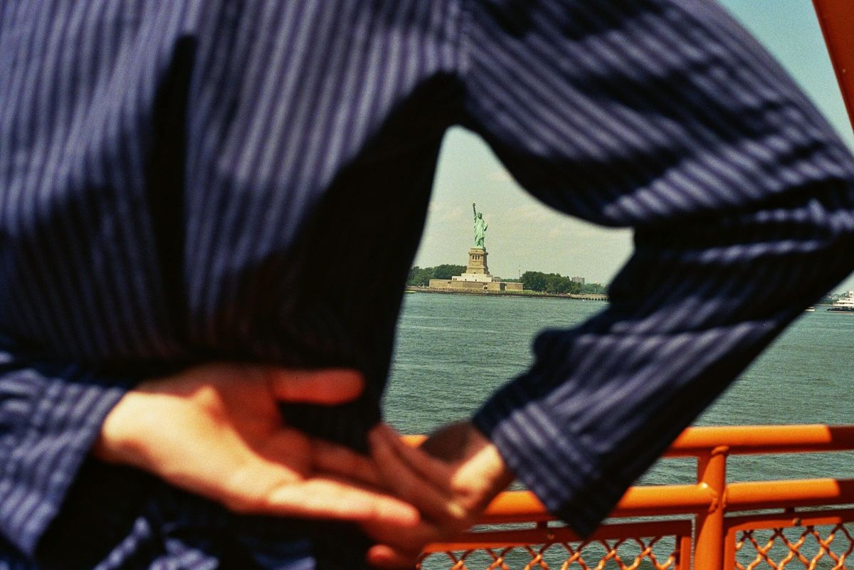 Statue of Liberty framed between someone's arched arm.