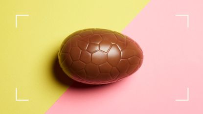 Milk chocolate Easter egg sitting whole on yellow and pink background, representing healthy chocolate