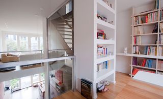 A floor in the building with white shelves of books and wooden floor.