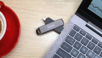 A promotional image of a SanDisk Extreme Pro Dual USB drive, shown inserted in the side of a laptop resting on a desk