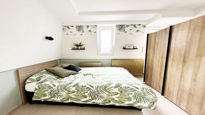 Gold radiator with bed with green palmtree duvet and green walls