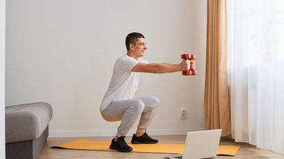 Man holding a dumbbell squat