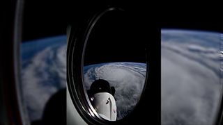 view through an orbiting spacecraft&#039;s window showing a large hurricane on earth below, with a white space capsule in the foreground