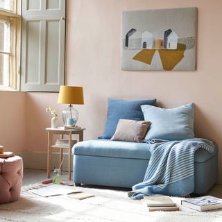 A pink living room with taupe painted shutters and a blue sofa bed