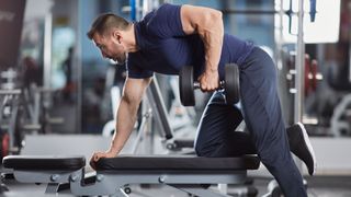 Man performing dumbbell row exercise in gym