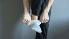 Close-up of man pulling a sock on, while balancing on one leg