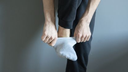 Close-up of man pulling a sock on, while balancing on one leg