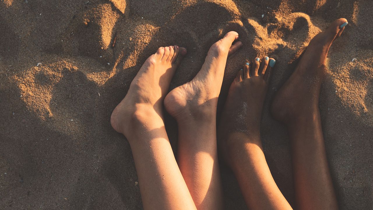 women&#039;s feet on the beach in the sand