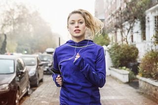 A woman jogging on the sidewalk of a residential street