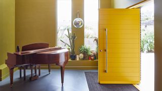 bright yellow front door in yellow hallway with piano