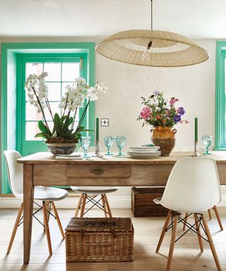 Dining room with wooden table and green/blue window frames