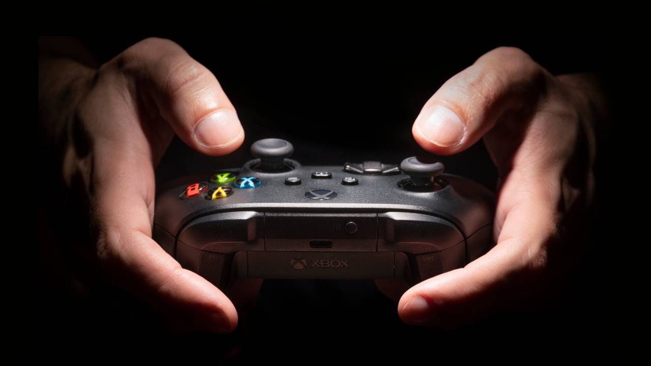 Seorang pria memegang pengontrol Xbox Series X dalam kegelapan