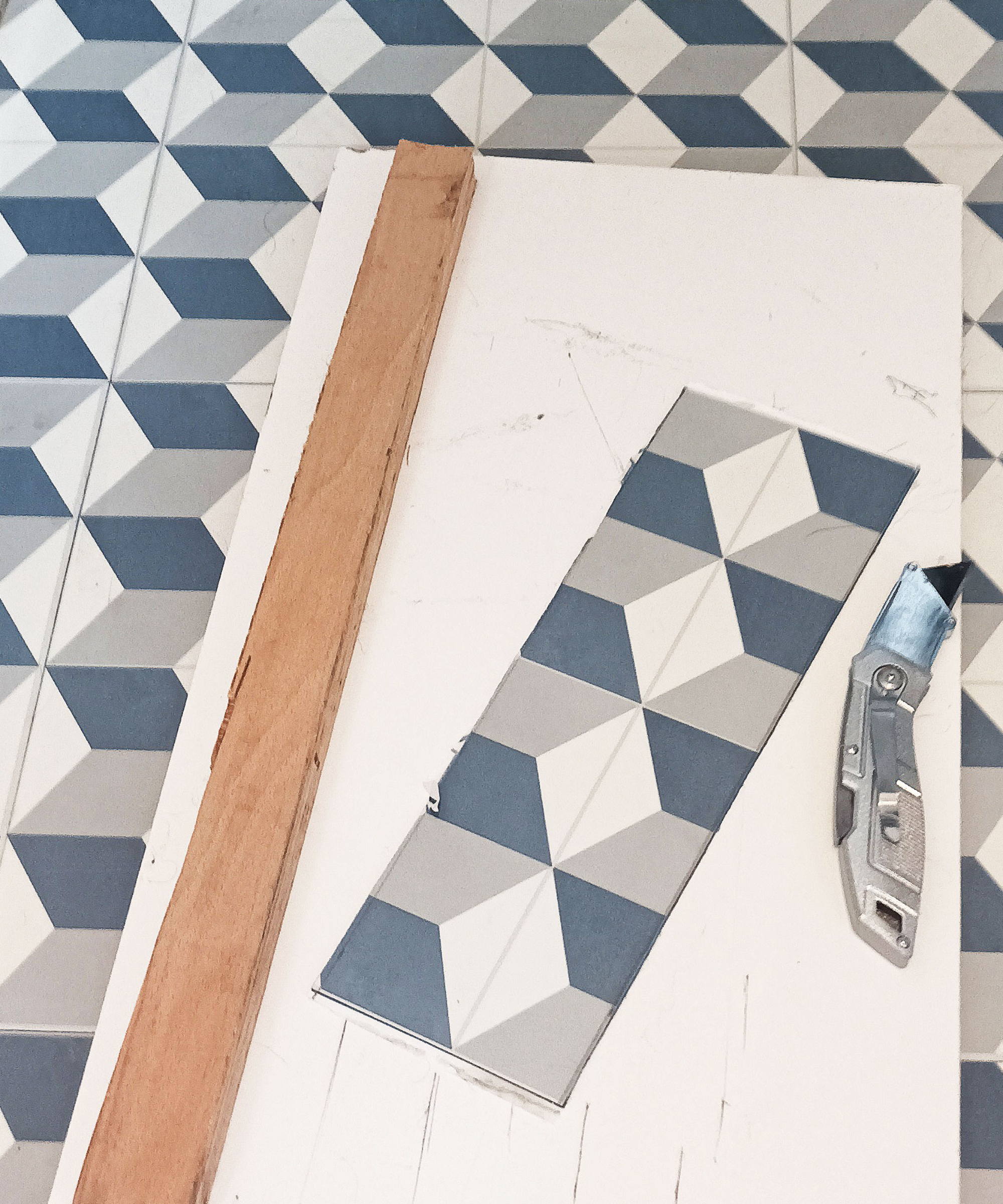 tiles being cut on board with straight edge and cutting knife