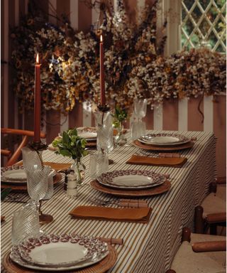 vintage inspired christmas table with striped tablecloth and striped wallpaper with a large foliage garland