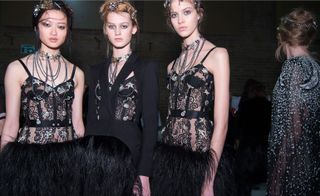 3 female models wearing black outfits of feathers & lace