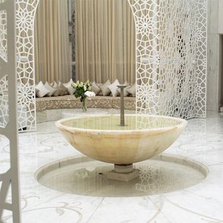 royal masour spa with designed curved sofa with cushions fountain bowl white mesh wall and designed floor