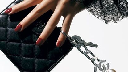 hand with lace sleeve holding a chanel wallet