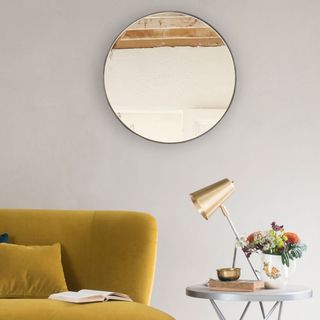 Loaf Jago mirror on wall with a yellow couch and a side table