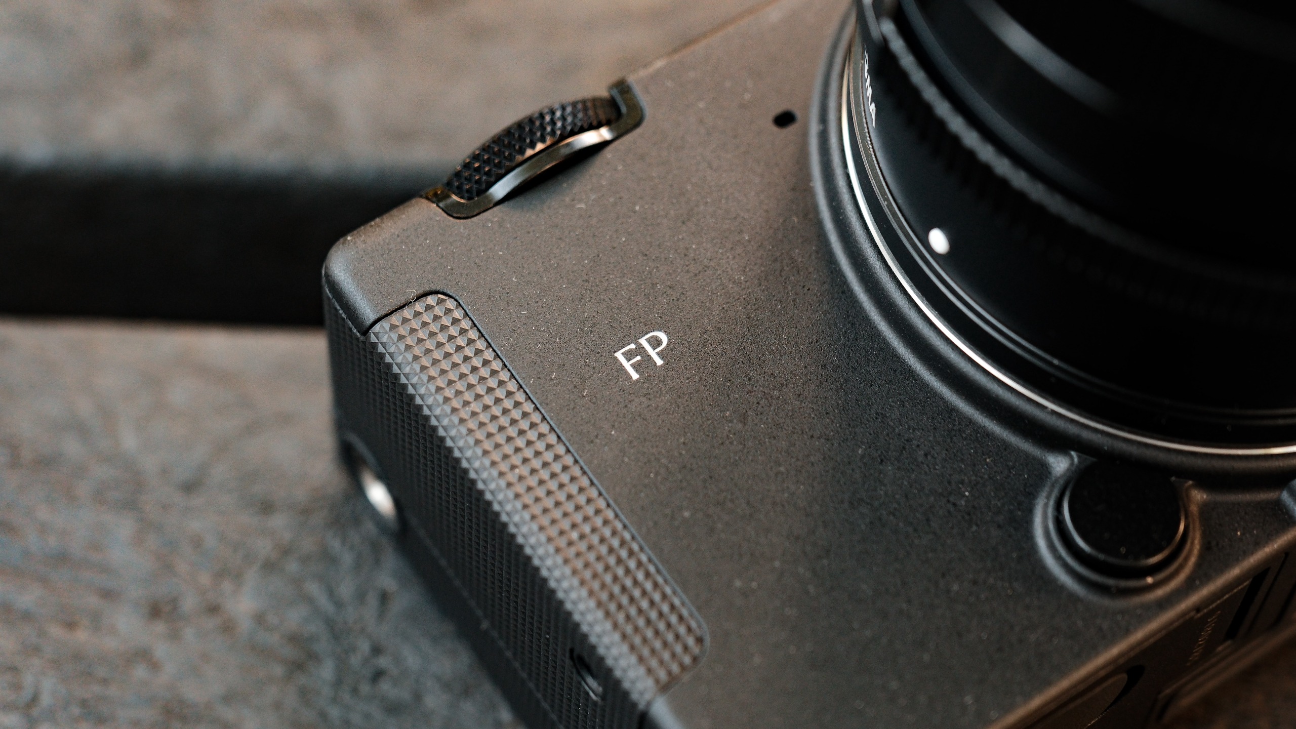 Close-up of the textured grip and FP branding on the front of the Sigma camera.